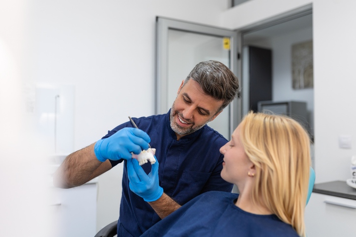 An expert dentist explaining dental crowns and bridges to a patient in Glendale, WI.